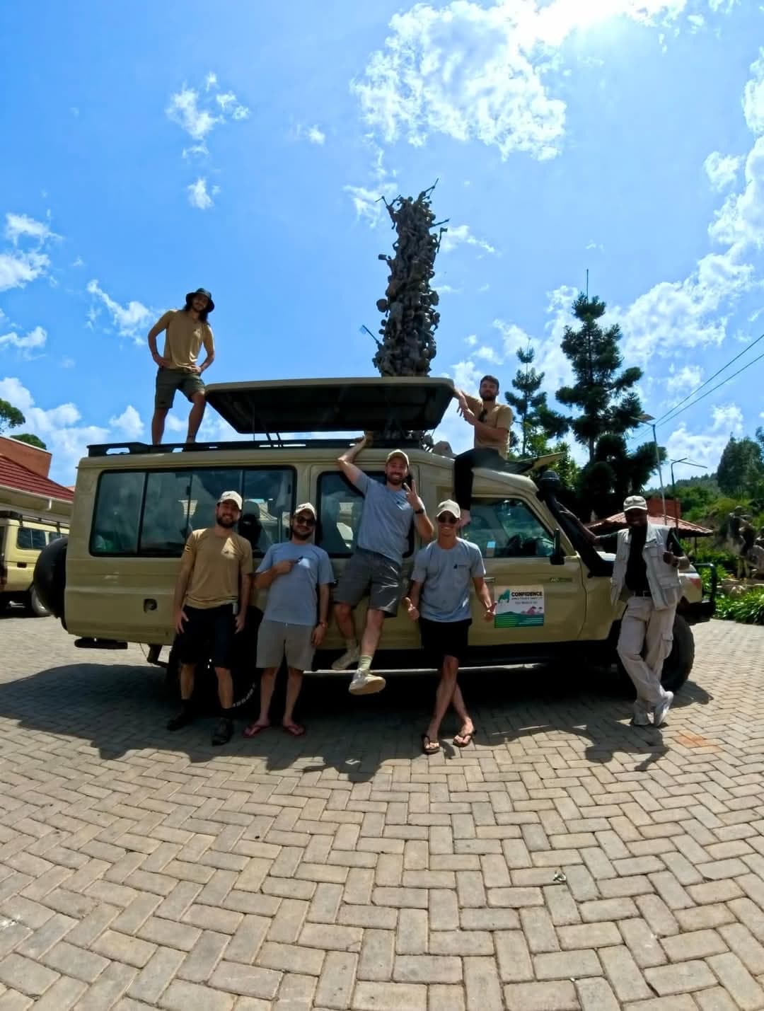 Eine Reisegruppe posiert auf und neben ihrem Safari-Land-Cruiser