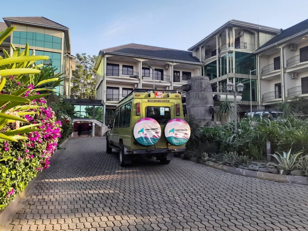 Un véhicule de safari de Confidence Africa Tours garé dans l’allée d’un hôtel