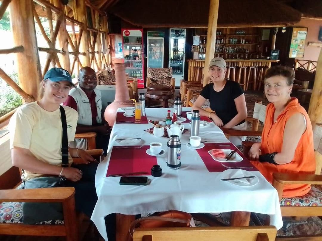 Viaggiatori a colazione con la loro guida nella sala da pranzo aperta di un lodge