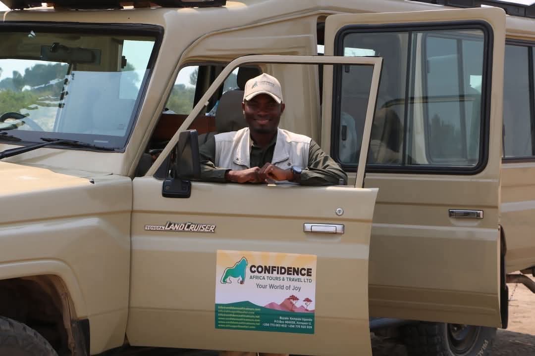 Ein Guide lehnt sich aus der offenen Tür eines Safarifahrzeugs von Confidence Africa Tours