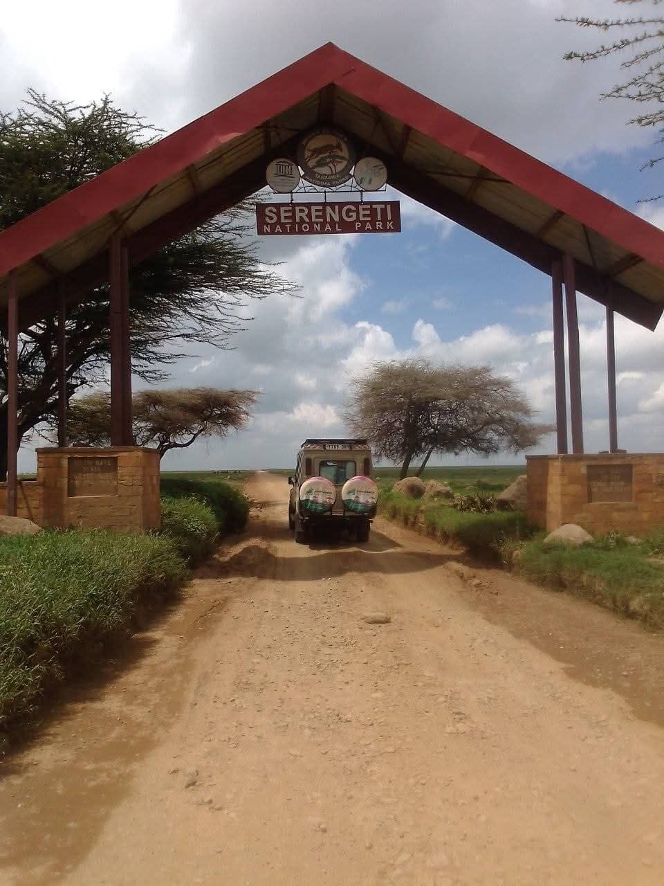 Ein Safarifahrzeug auf der Schotterstraße unter dem Eingangstor des Serengeti-Nationalparks