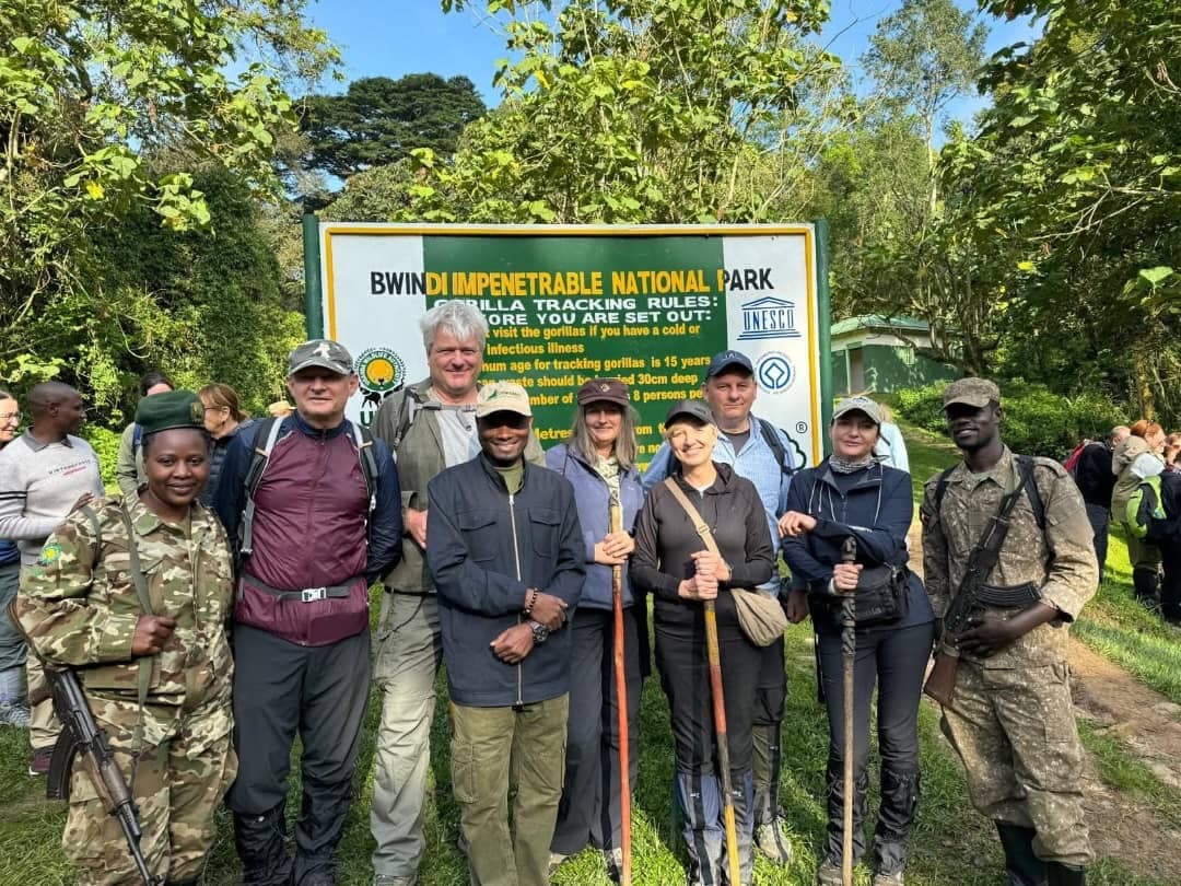 Eine Trekkinggruppe mit Rangern der Uganda Wildlife Authority am Schild für das Gorilla-Tracking im Bwindi-Impenetrable-Nationalpark